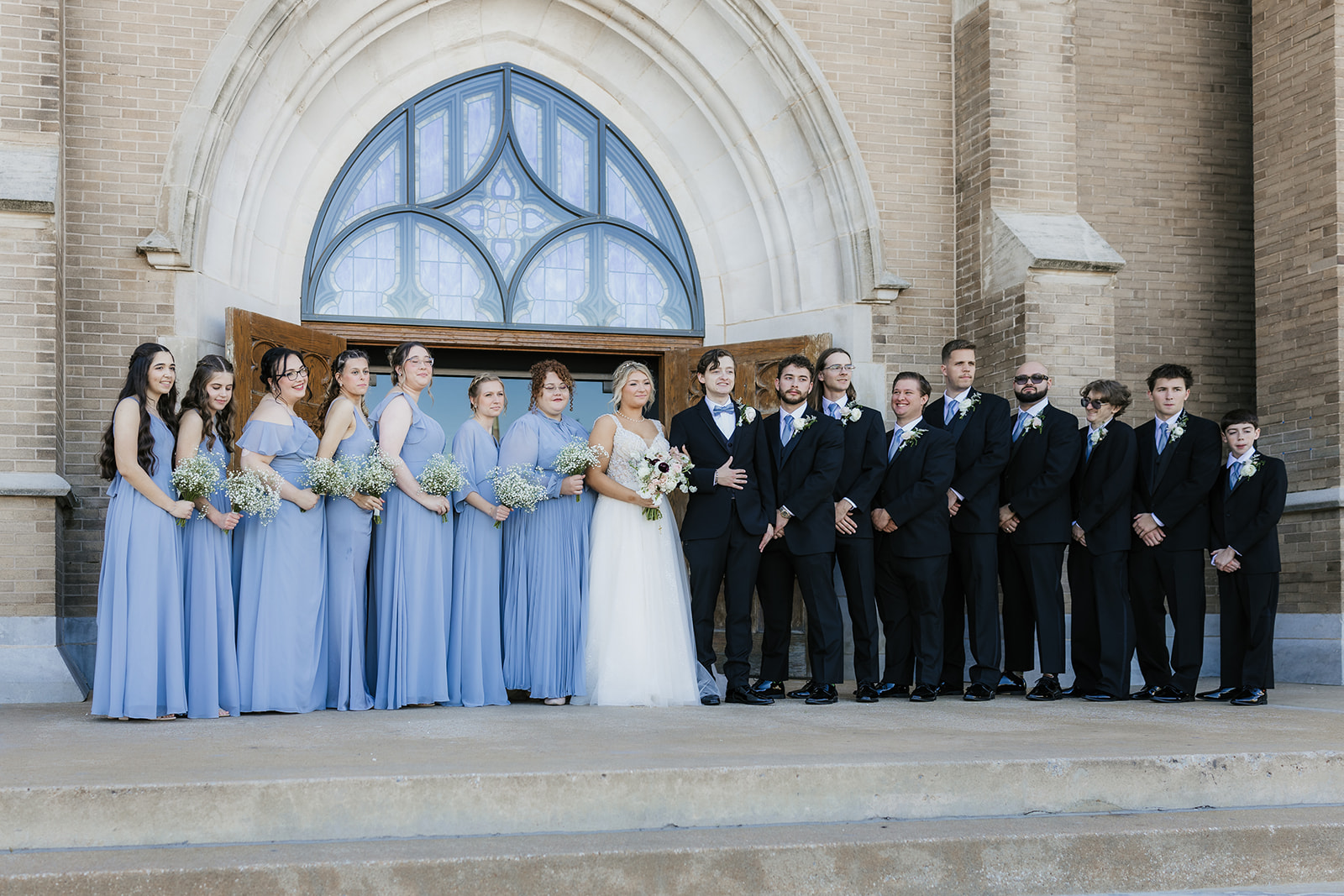 bride and groom take wedding party portraits outside the cathedral