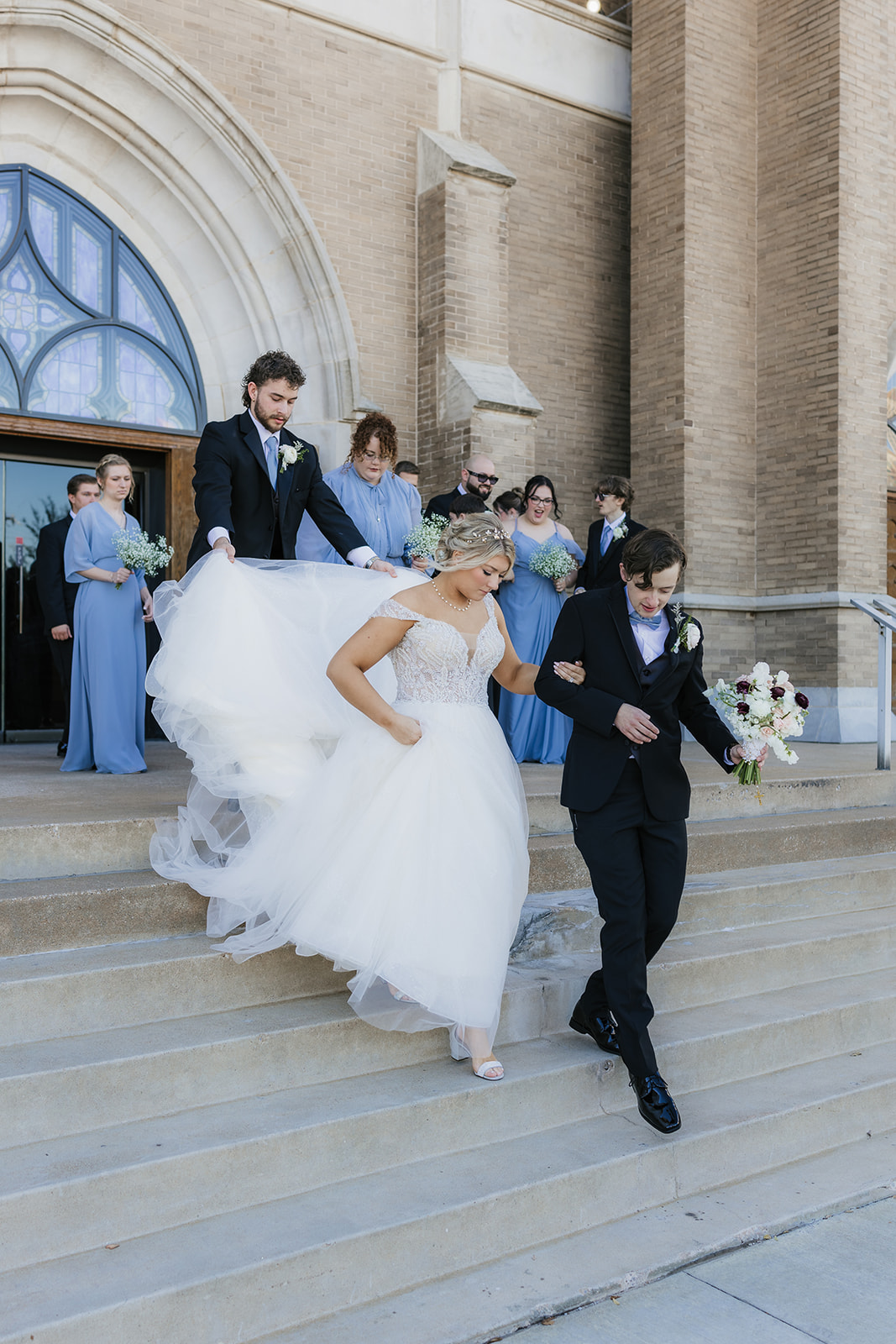 bride and groom take wedding party portraits outside the cathedral