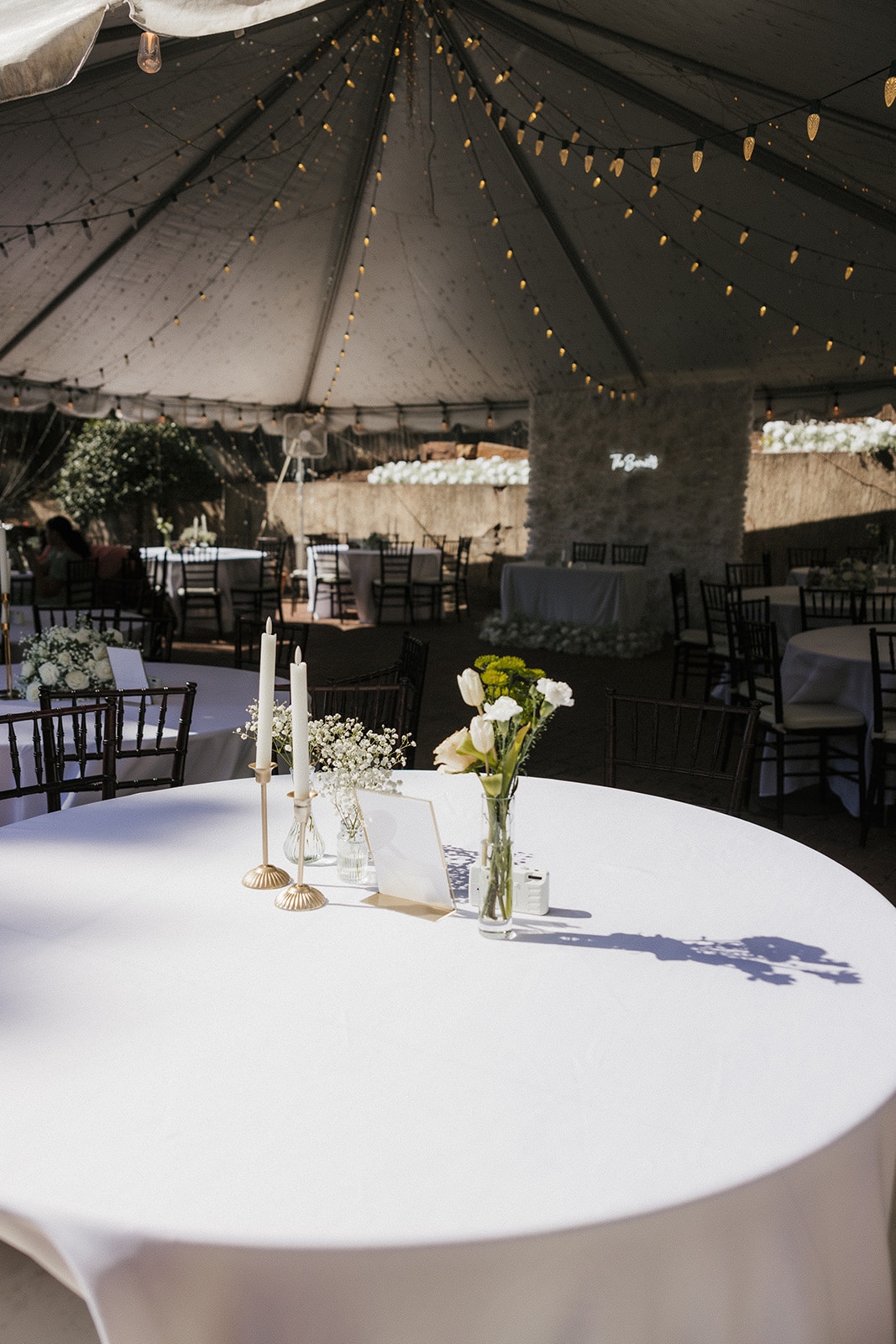 Outdoor wedding ceremony setup with white chairs and floral arrangements lining a central aisle, set against a backdrop of trees and a rustic building. | Top 6 Historic Mansion Wedding Venues in Tulsa