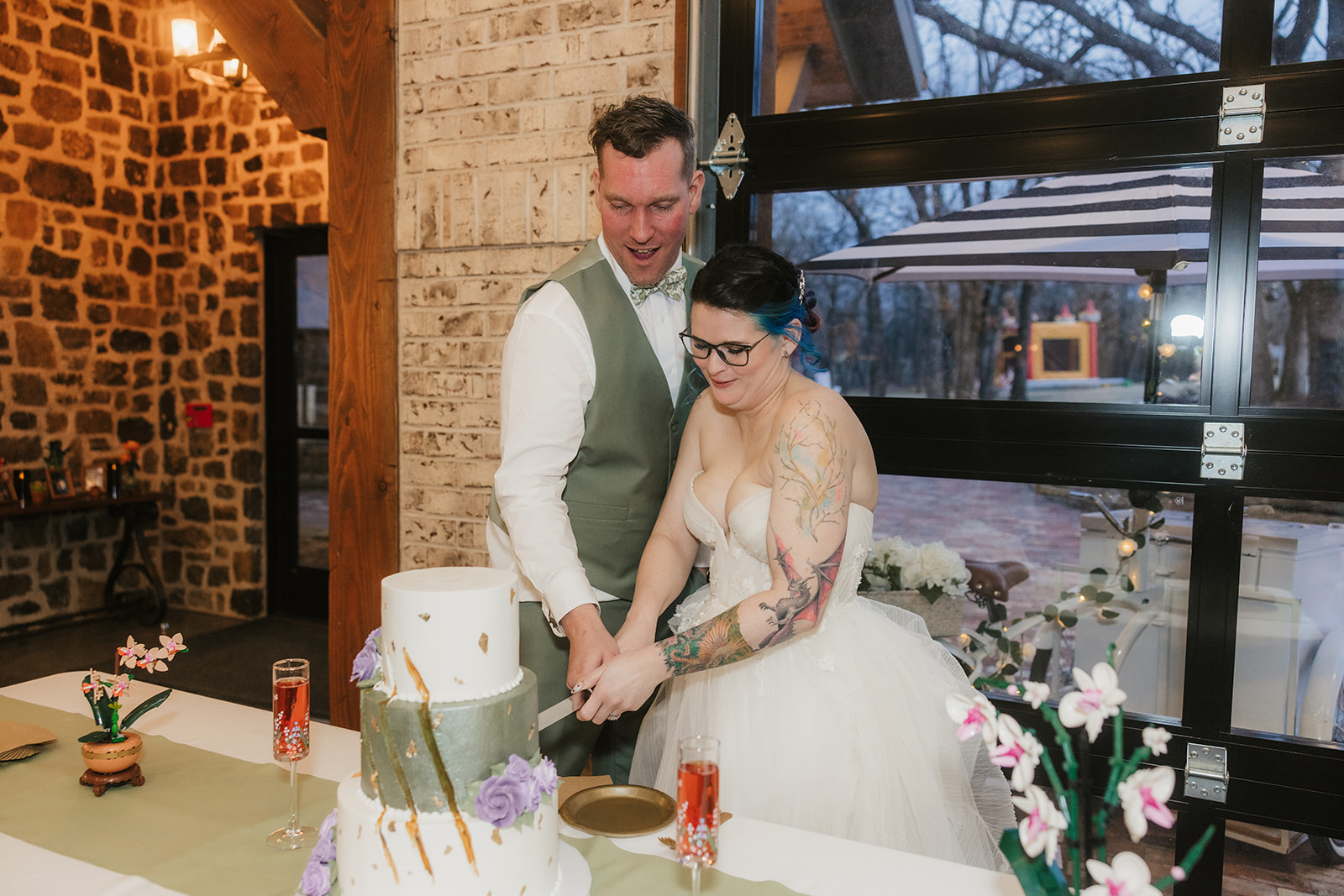 A bride and groom smiling as they cut their wedding cake together at a decorated indoor venue for their wedding at Discoveryland Ranch