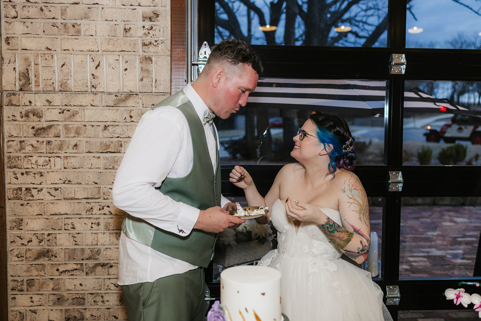 A bride and groom smiling as they cut their wedding cake together at a decorated indoor venue for their wedding at Discoveryland Ranch