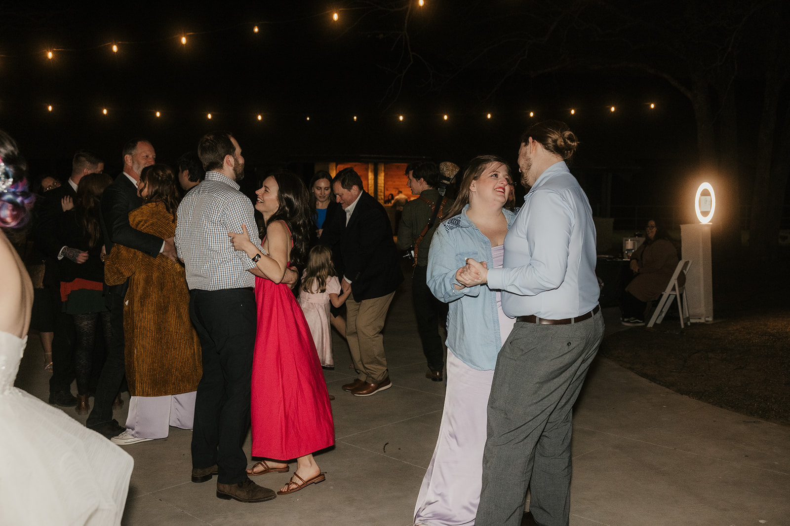 people dance on the dance floor outdoors at a wedding
