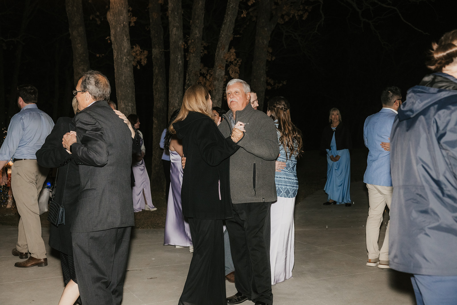 people dance on the dance floor outdoors at a wedding