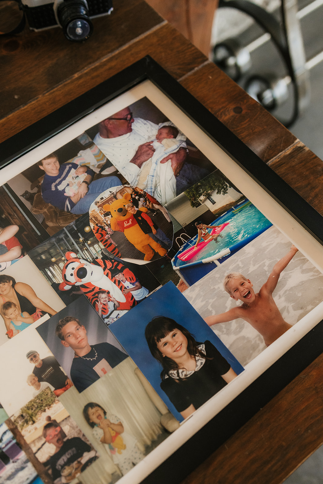 A framed collage of various childhood and family photos, including children, a pool scene, and someone in a tiger costume, displayed on a wooden surface.