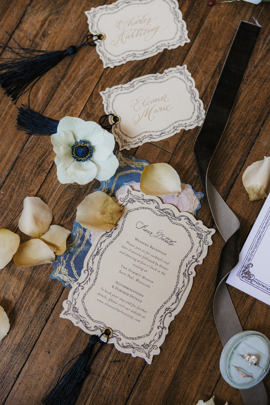 Flat lay of wedding invitations, floral arrangements, a beaded necklace, a photo, and decorative items arranged on a wooden floor for catholic wedding ideas