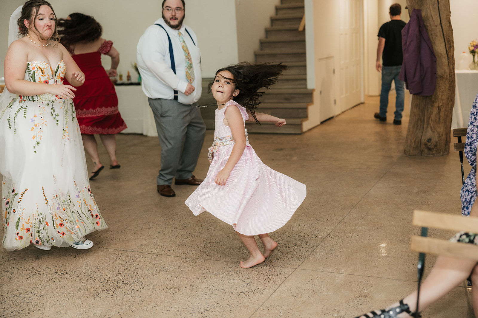 A bride and groom dance together in an open indoor space, with several guests standing and sitting in the background for their wedding at Merrick Hollow 