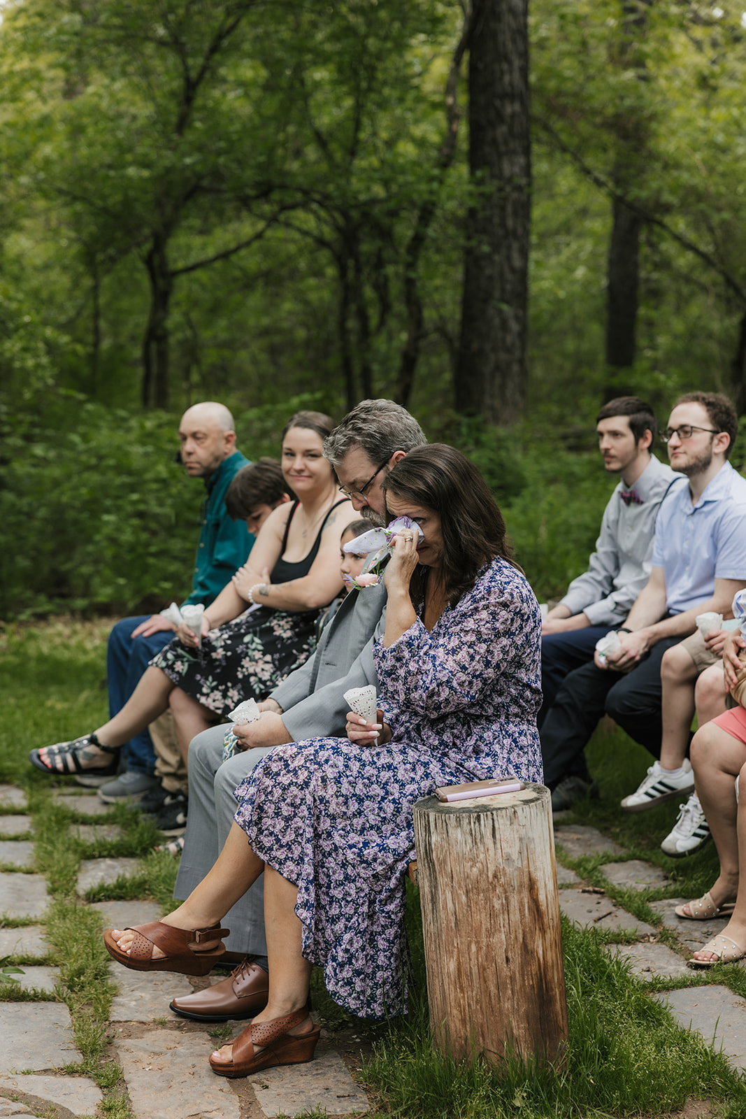 A couple under a geometric arch draped with white fabric during an outdoor wedding ceremony as guests watch and applaud for a wedding at Merrick Hollow Wedding
