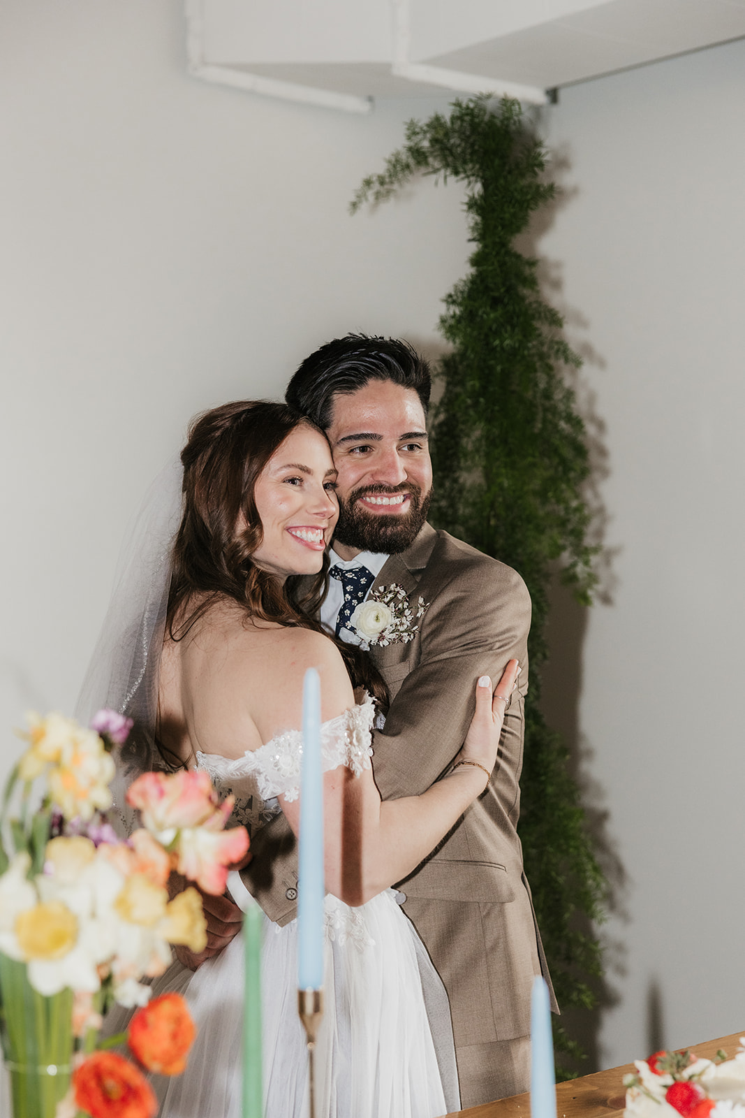 A bride and groom cut a wedding cake together at a decorated table with flowers and candles.