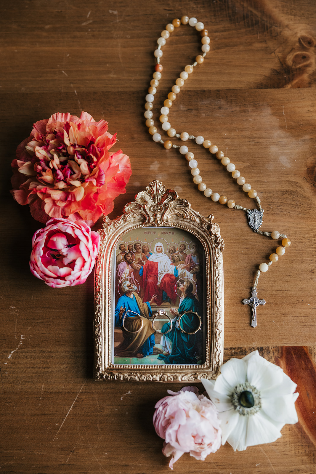 A blue and white decorative plate with strawberries and a porcelain egg, surrounded by flowers, beads, and white fabric on a wooden surface for spring wedding inspo