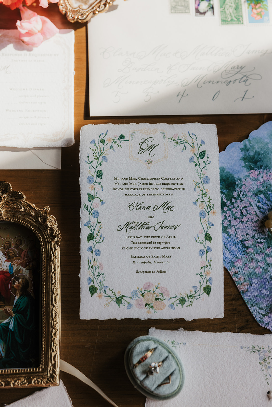 A flat lay of wedding stationery, invitations, vintage frames, ribbon, flowers, and assorted decorative items arranged on a wooden table.