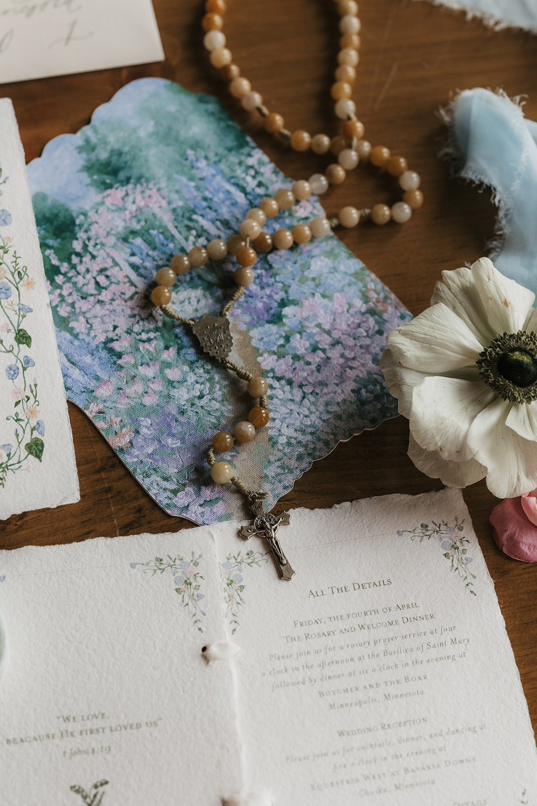 A flat lay of wedding stationery, invitations, vintage frames, ribbon, flowers, and assorted decorative items arranged on a wooden table.