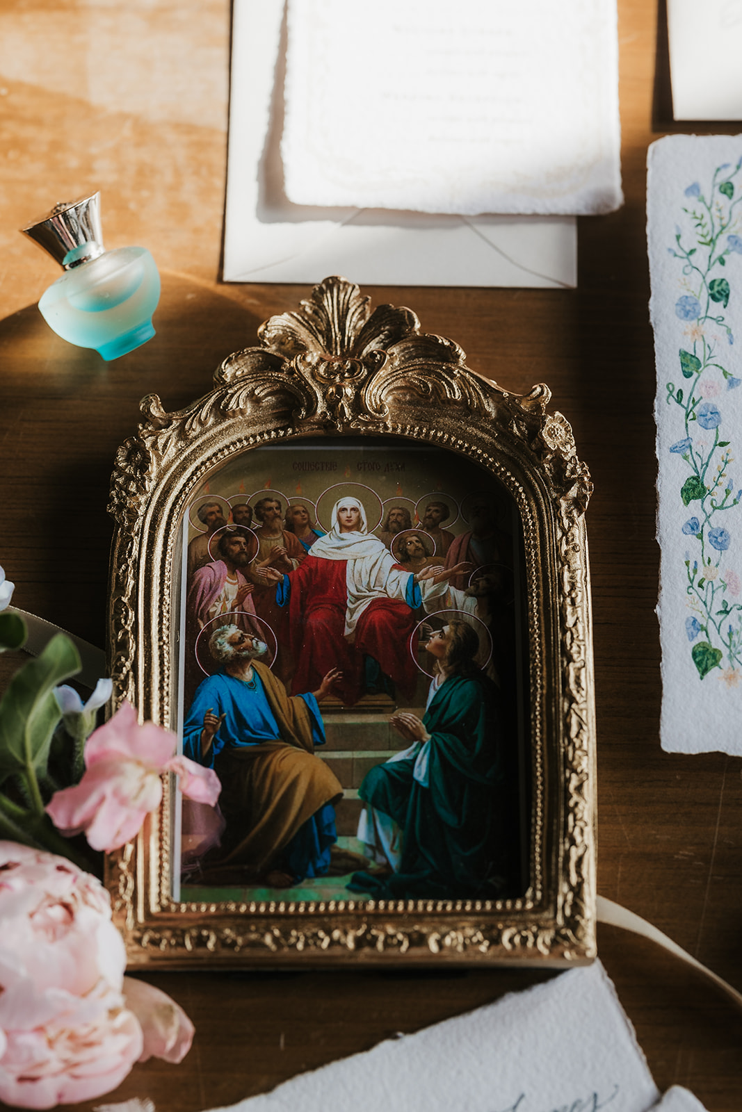 A flat lay of wedding stationery, invitations, vintage frames, ribbon, flowers, and assorted decorative items arranged on a wooden table.