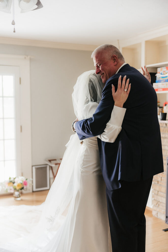 A man in a suit smiles while dancing with a woman in a white wedding dress and veil indoors for a wedding at St. Thomas More University Parish