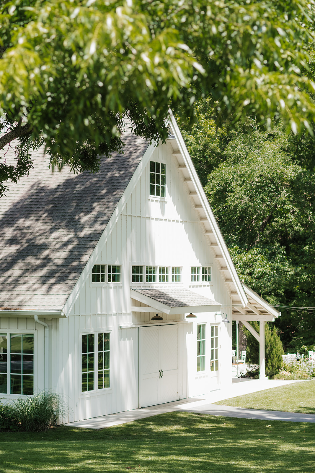 Single-story white house with a large, sloped roof, surrounded by trees and greenery, with a curved driveway in front at a spain ranch wedding