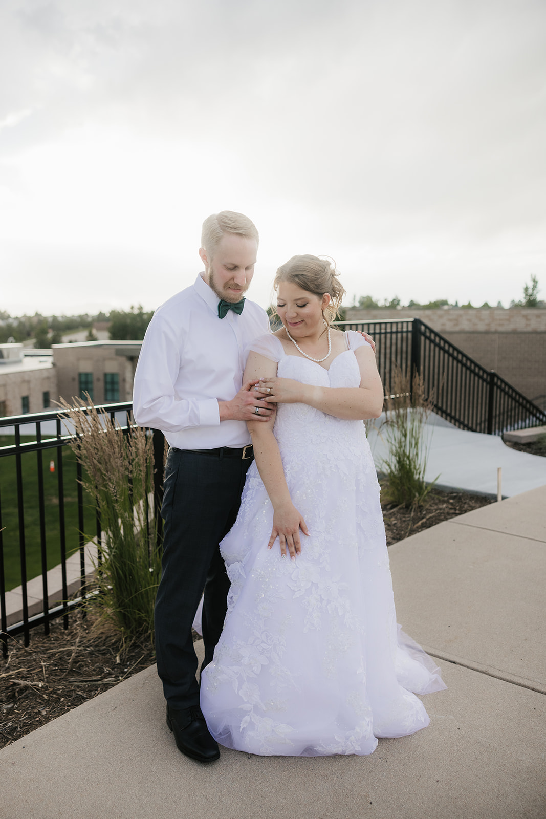 catholic wedding photos of A bride and groom kiss on an outdoor terrace with a scenic view of mountains, cloudy sky, and a town in the background.