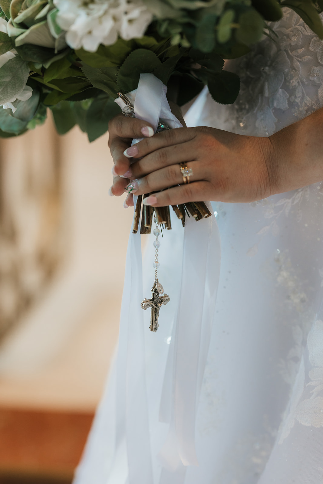 Catholic Wedding Photos of a bride and groom stand together in front of an altar inside a church, with the bride holding a bouquet and a large crucifix visible in the background.