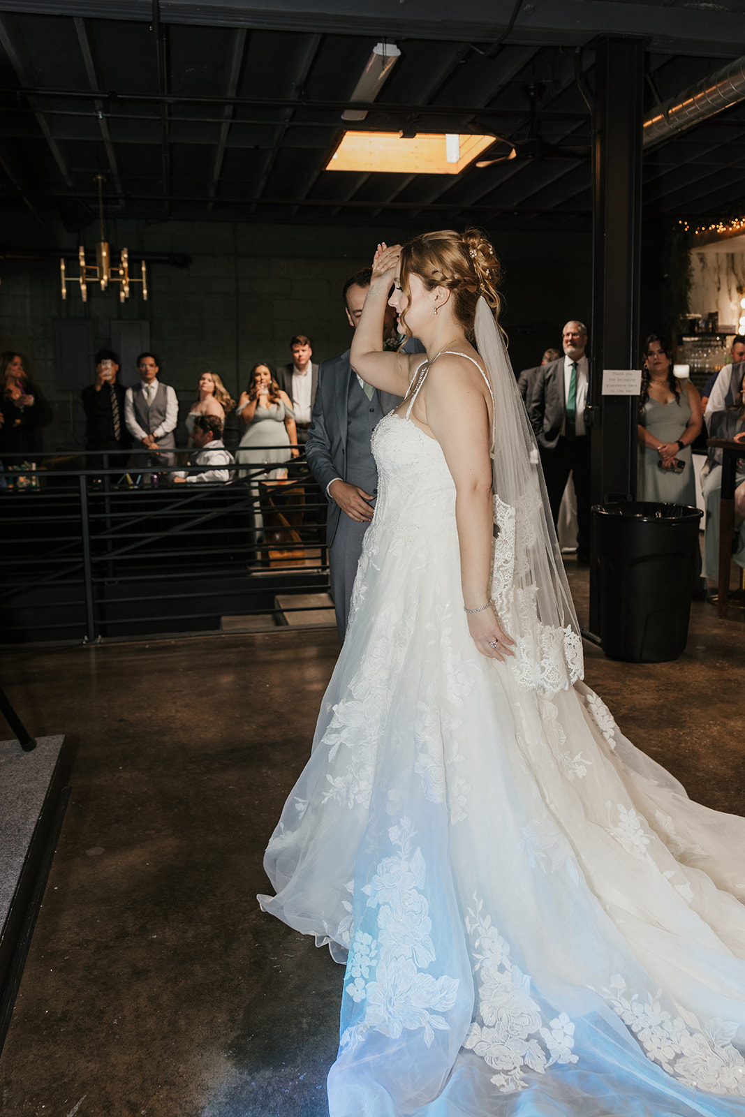 A bride and groom share a dance at their wedding reception indoors, with guests and decorations visible in the background at a Camp Loughridge Wedding