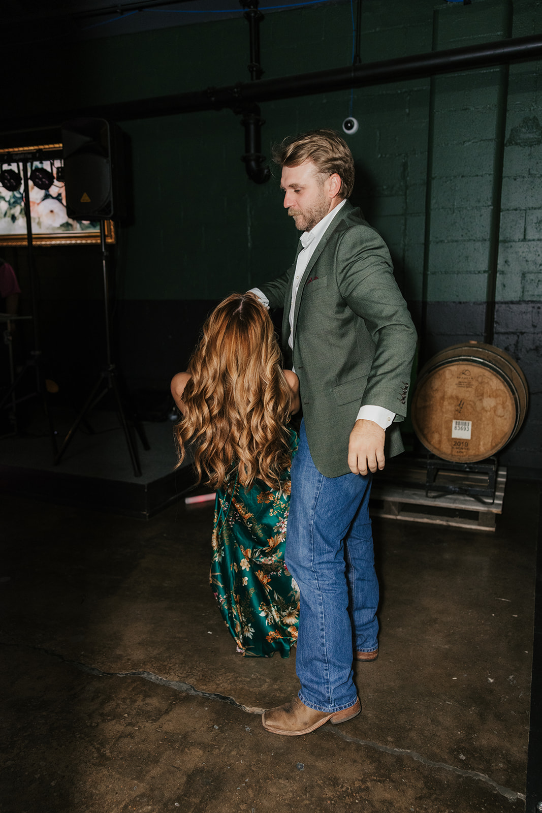 A bride and guests, holding light-up sticks, dance and celebrate together at an indoor wedding reception for a wedding at Camp Loughridge Wedding