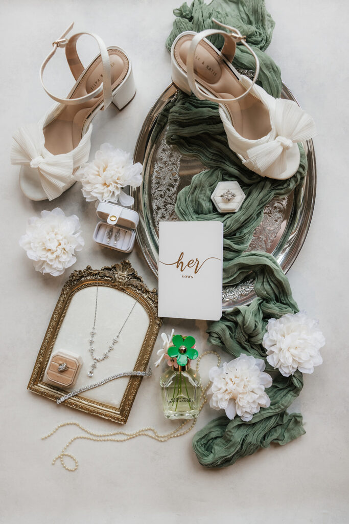 Flat lay of elegant wedding invitations, RSVP cards, envelopes, and white flowers arranged on a light surface.