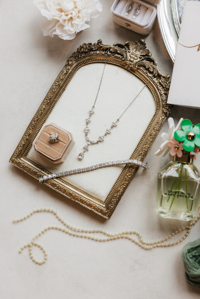 Flat lay of elegant wedding invitations, RSVP cards, envelopes, and white flowers arranged on a light surface.