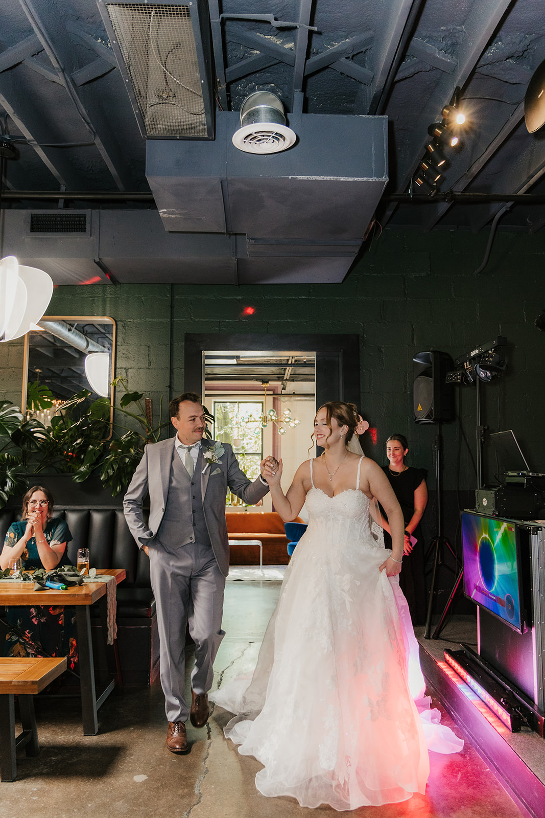 A bride and groom share a dance at their wedding reception indoors, with guests and decorations visible in the background at a Camp Loughridge Wedding