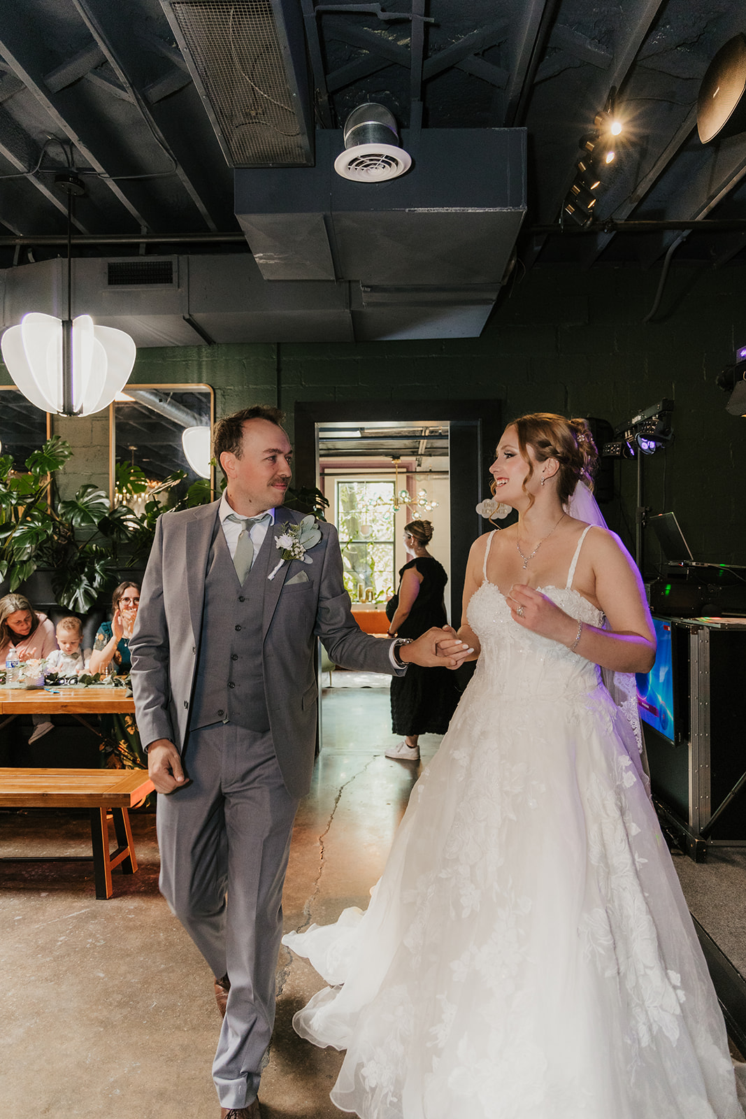 A bride and groom share a dance at their wedding reception indoors, with guests and decorations visible in the background at a Camp Loughridge Wedding