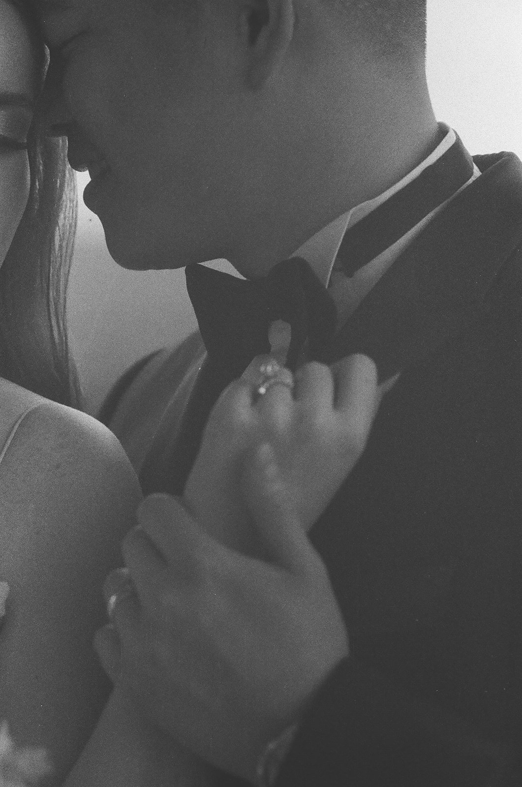 A couple dressed in formal attire, with the woman in a wedding gown, stands on a balcony looking outward in a black and white photo | unique wedding design