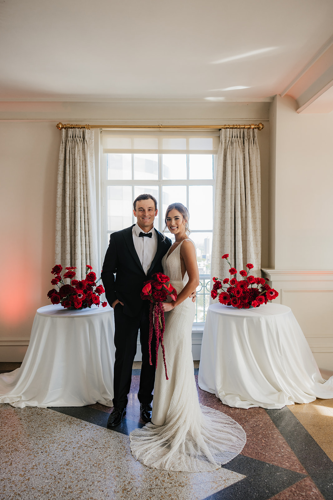A bride in a white dress holds a piece of paper and smiles at a groom in a dark suit during a wedding ceremony indoors for a wedding at the mayo hotel
