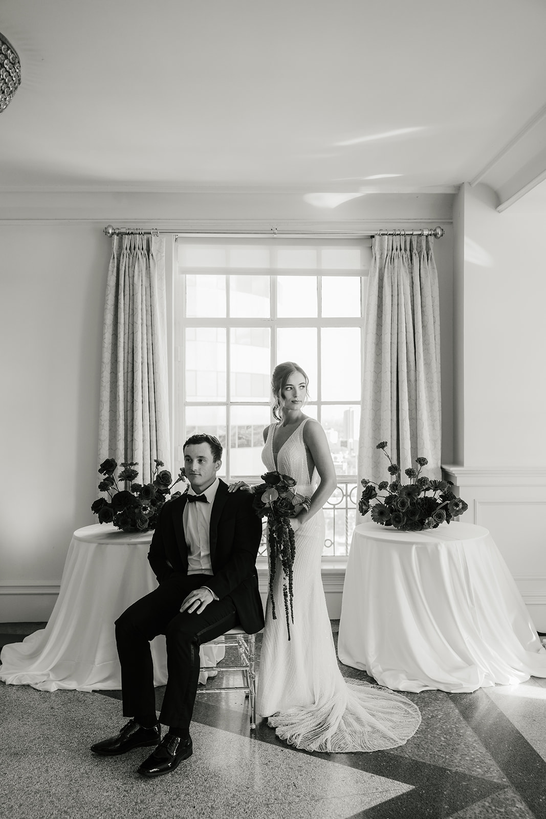 A bride in a white dress holds a piece of paper and smiles at a groom in a dark suit during a wedding ceremony indoors for a wedding at the mayo hotel