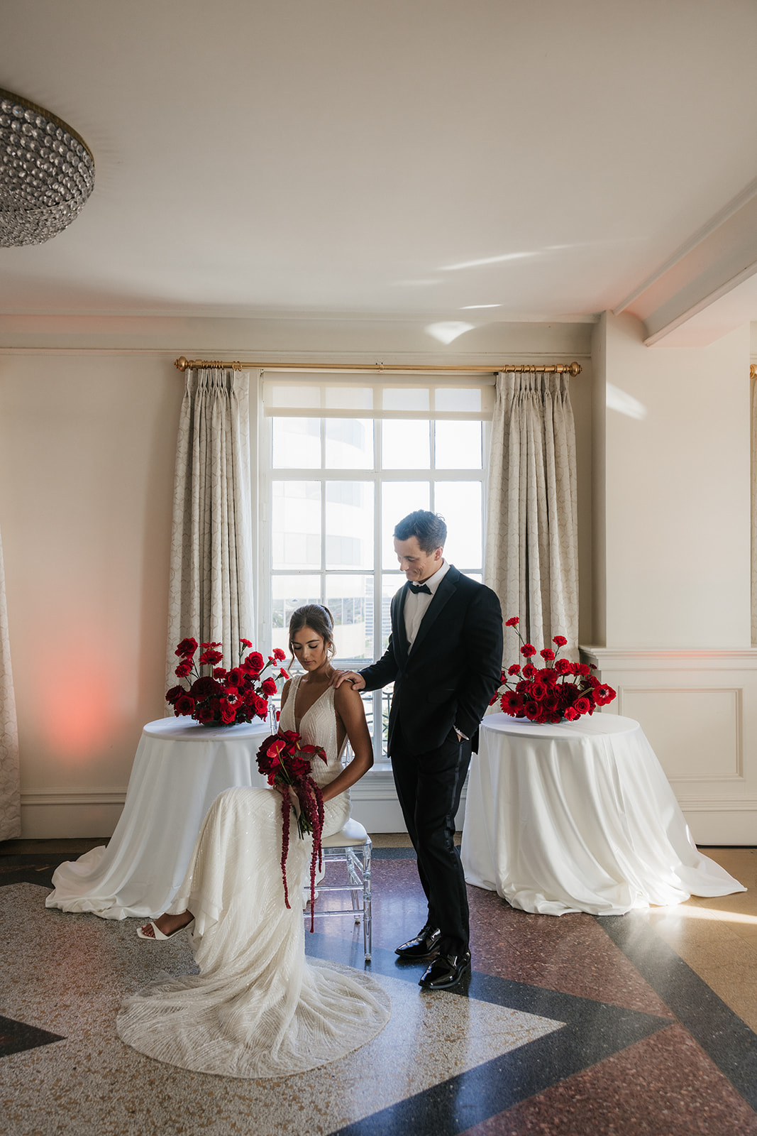 A bride in a white dress holds a piece of paper and smiles at a groom in a dark suit during a wedding ceremony indoors for a wedding at the mayo hotel