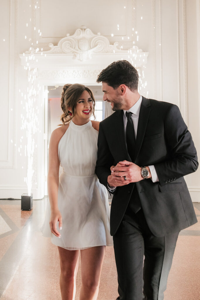 A couple dressed formally dances in a decorative room, with sparklers on each side of the doorway and natural light coming in from a window behind them for a mayo hotel wedding
