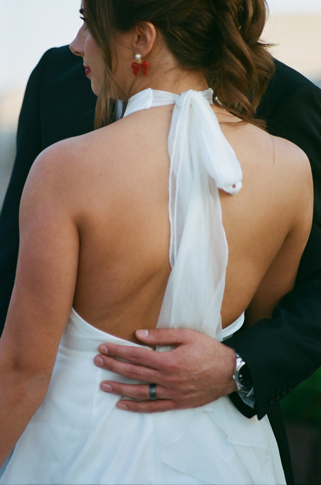 A bride in a white dress and a groom in a black suit stand close together on an outdoor terrace, looking at each other at the mayo hotel