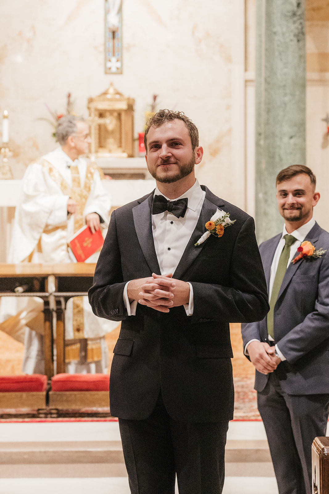 A bride and groom stand at the altar in a church during their wedding ceremony, with guests seated on both sides.