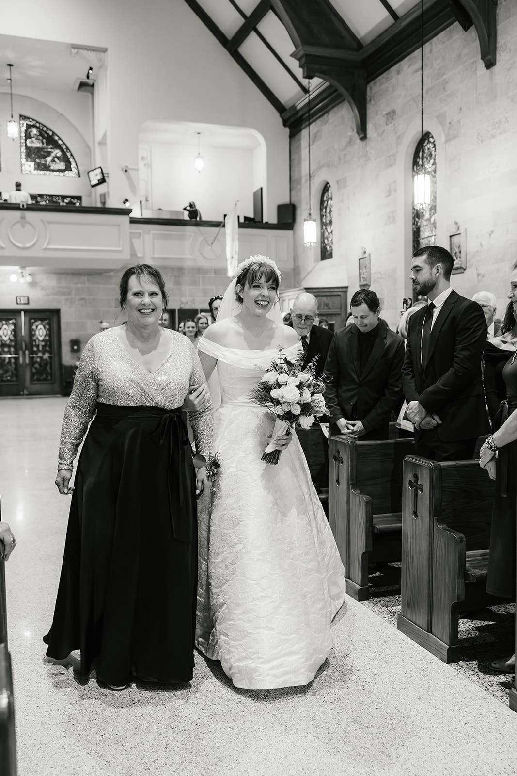 A bride and groom stand at the altar in a church during their wedding ceremony, with guests seated on both sides.