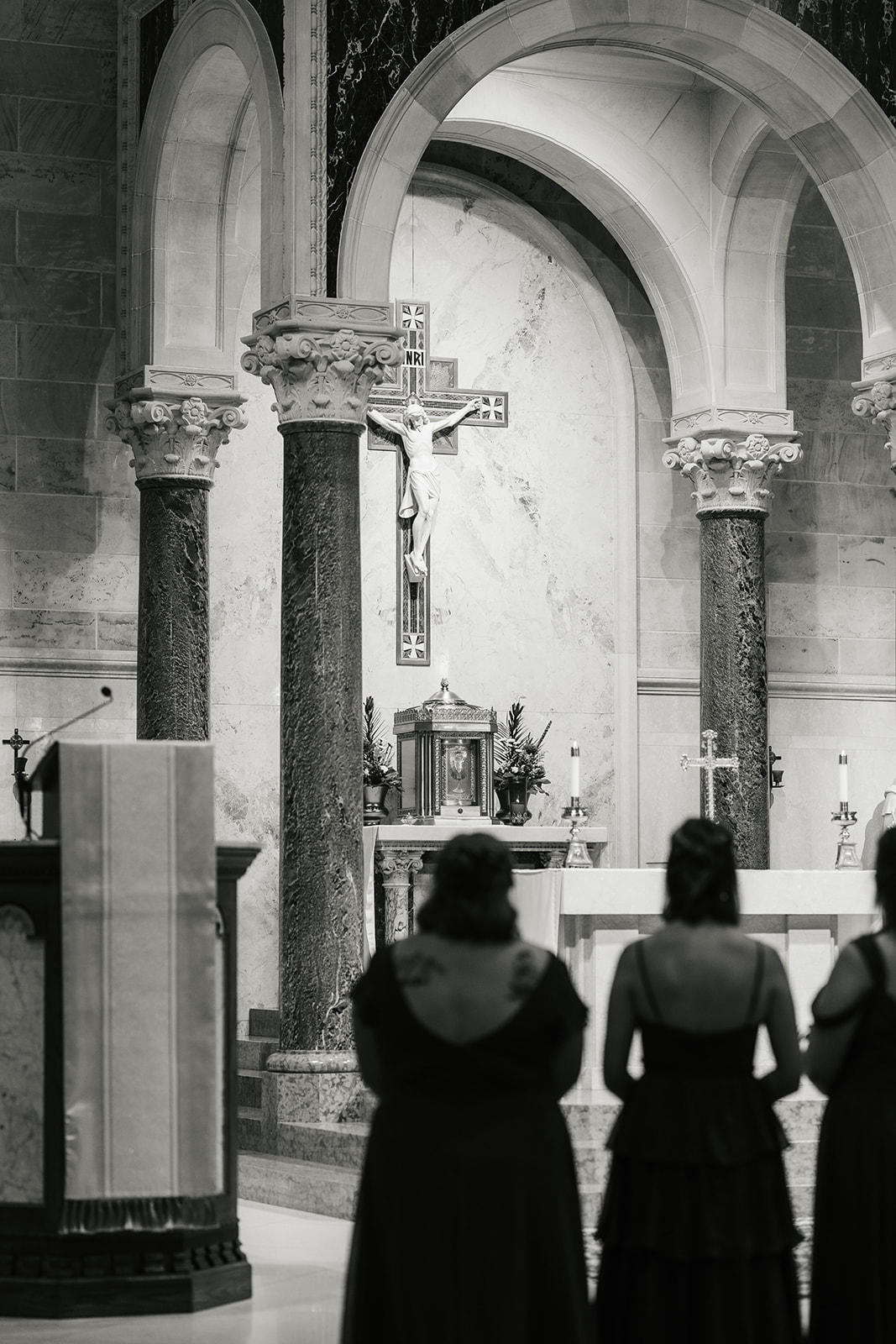 A bride and groom stand at the altar in a church during their wedding ceremony, with guests seated on both sides.