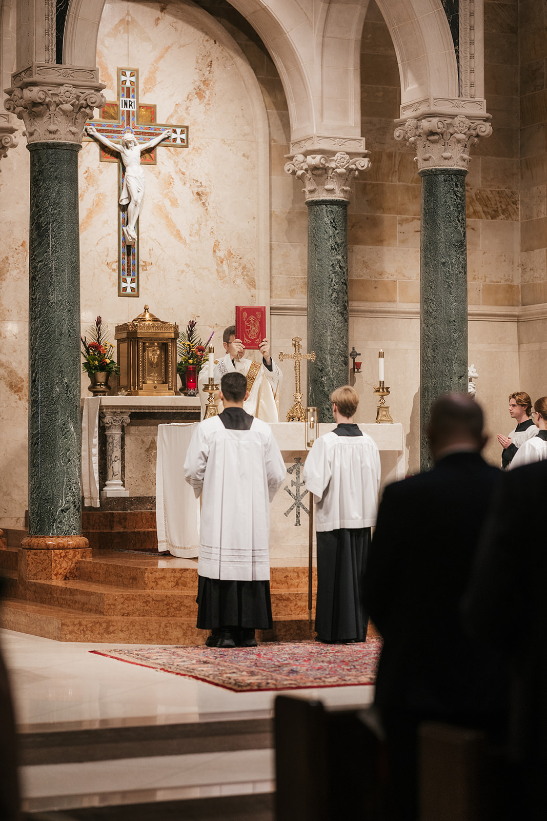 A bride and groom stand at the altar in a church during their wedding ceremony, with guests seated on both sides.