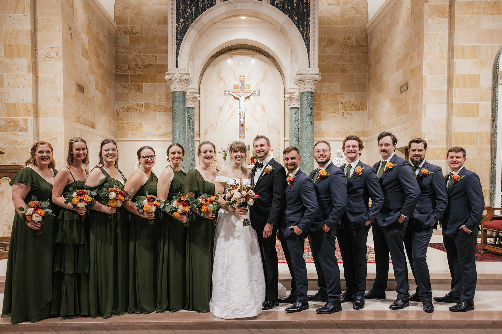 A bride and groom stand together in a church with five clergy members, all dressed in formal attire, posing for a wedding photo.