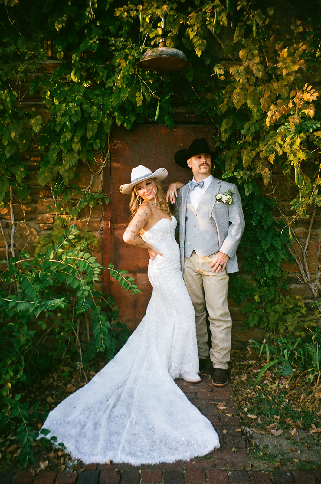 A bride and groom stand close together under a flowing veil outdoors; the bride wears a white dress and the groom a light gray suit with a floral boutonniere at aWedding at The Silo Event Center in Tulsa