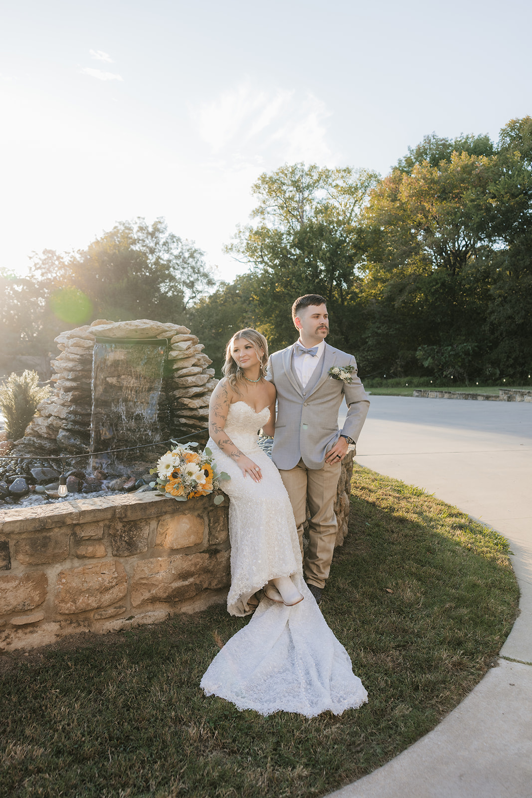 A bride and groom stand close together under a flowing veil outdoors; the bride wears a white dress and the groom a light gray suit with a floral boutonniere at aWedding at The Silo Event Center in Tulsa