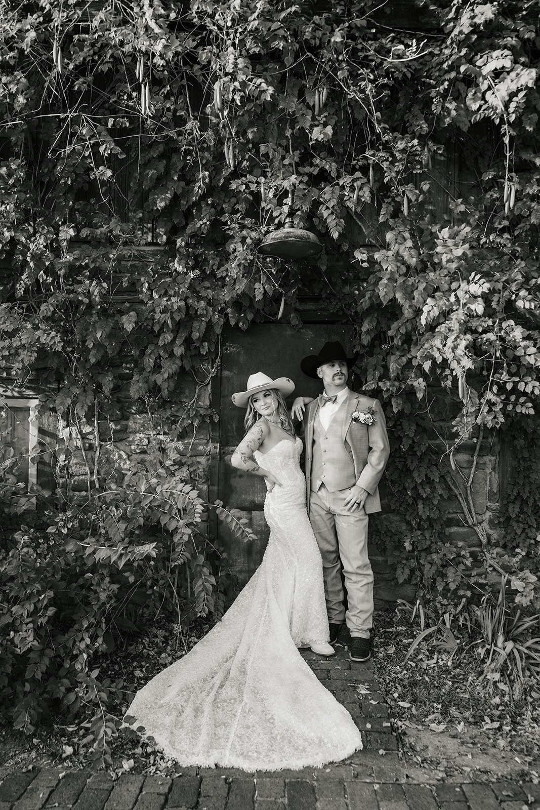 A bride and groom stand close together under a flowing veil outdoors; the bride wears a white dress and the groom a light gray suit with a floral boutonniere at aWedding at The Silo Event Center in Tulsa