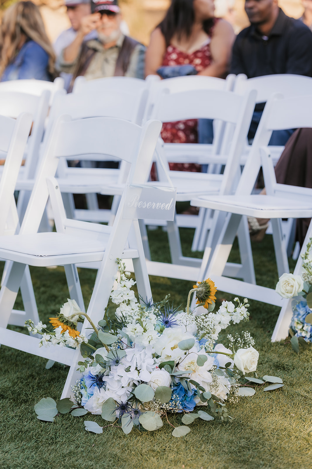 A bride and groom kiss under a white pergola during an outdoor wedding ceremony, with guests and an officiant present at The Silo Event Center in Tulsa