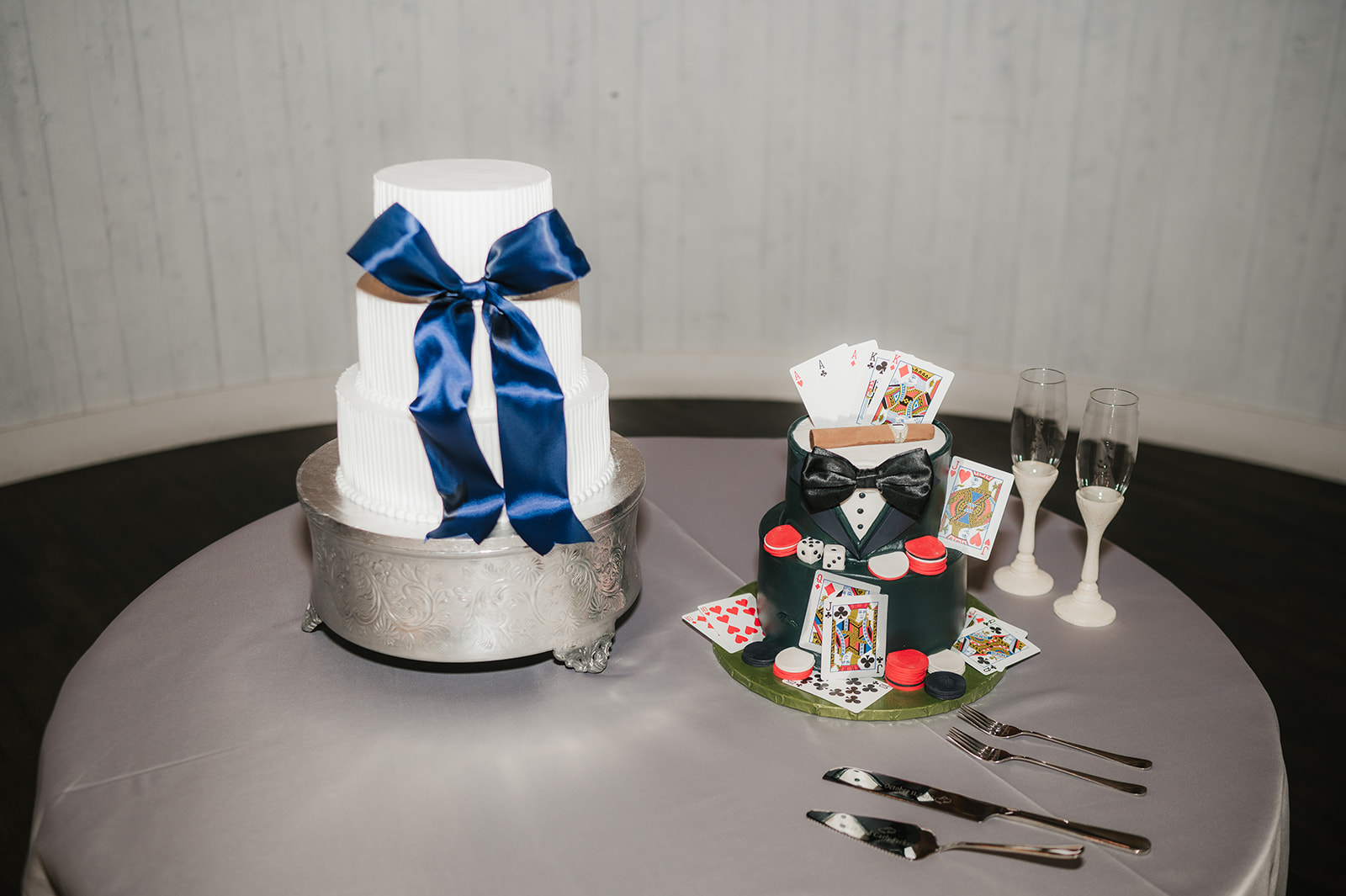 A bride and groom wearing cowboy hats feed each other cake beside a decorated wedding cake and glasses of champagne.