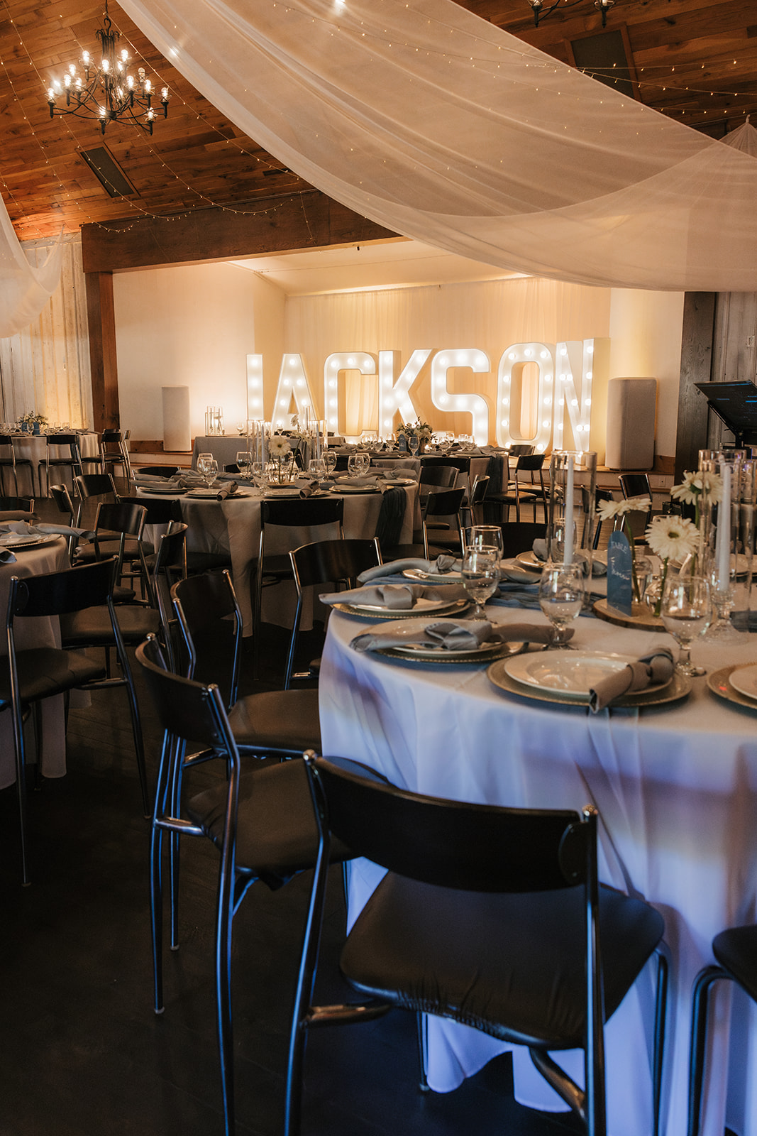 A round table set for a formal event with white plates, silverware, water glasses, cloth napkins, and a flower centerpiece labeled “Table Four.”.