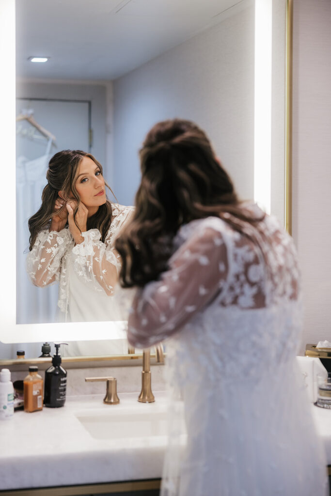 bride putting on her jewelry before the ceremony