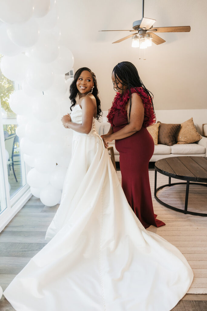 Mother of the bride helping her with the wedding dress