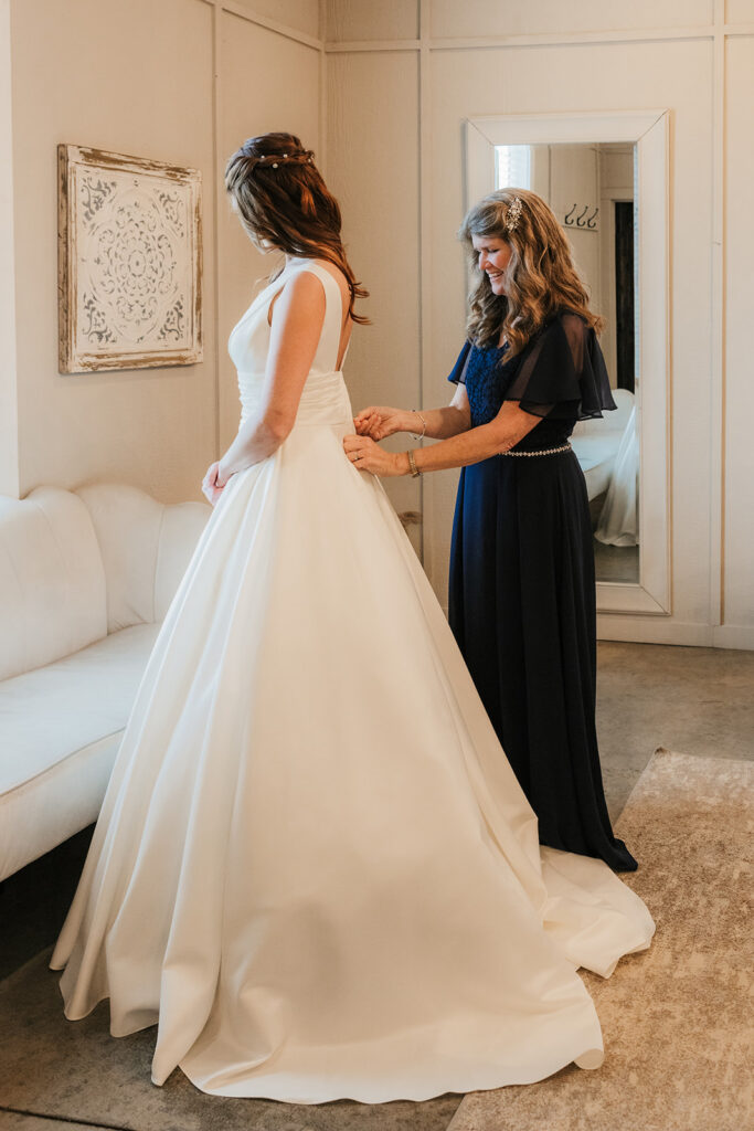 mother of the bride helping her with the wedding dress