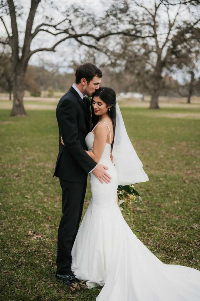 groom kissing the bride on the forehead