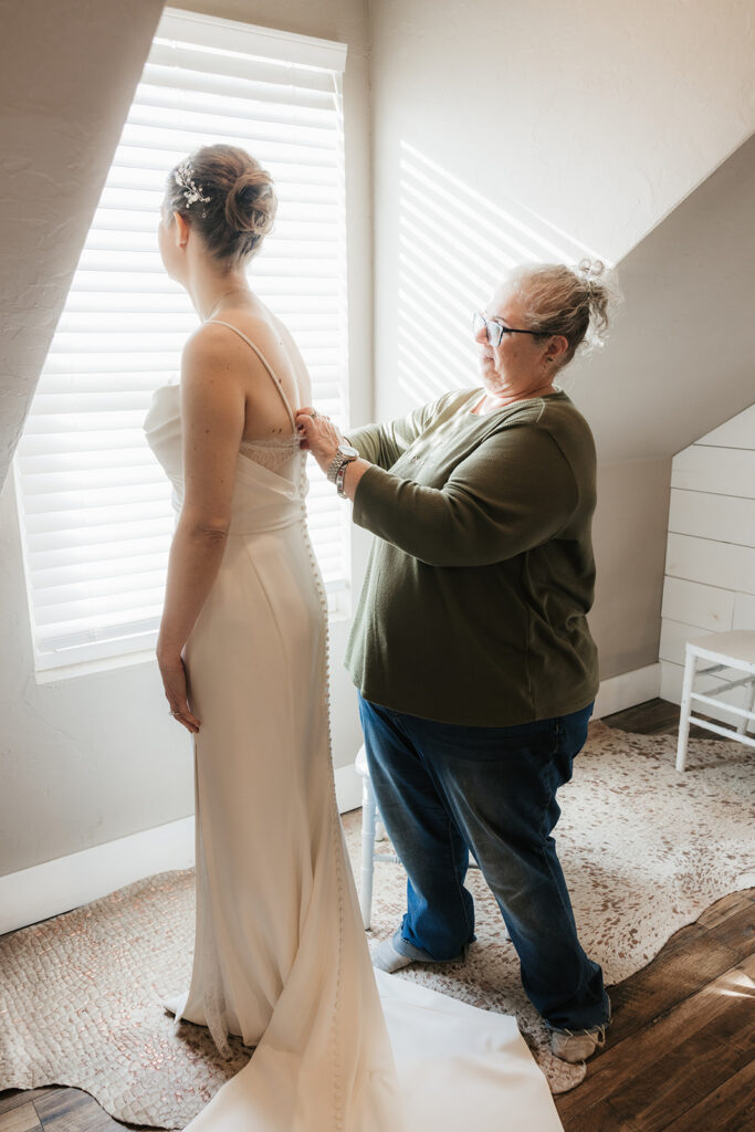 mother of the bride helping her with her wedding dress