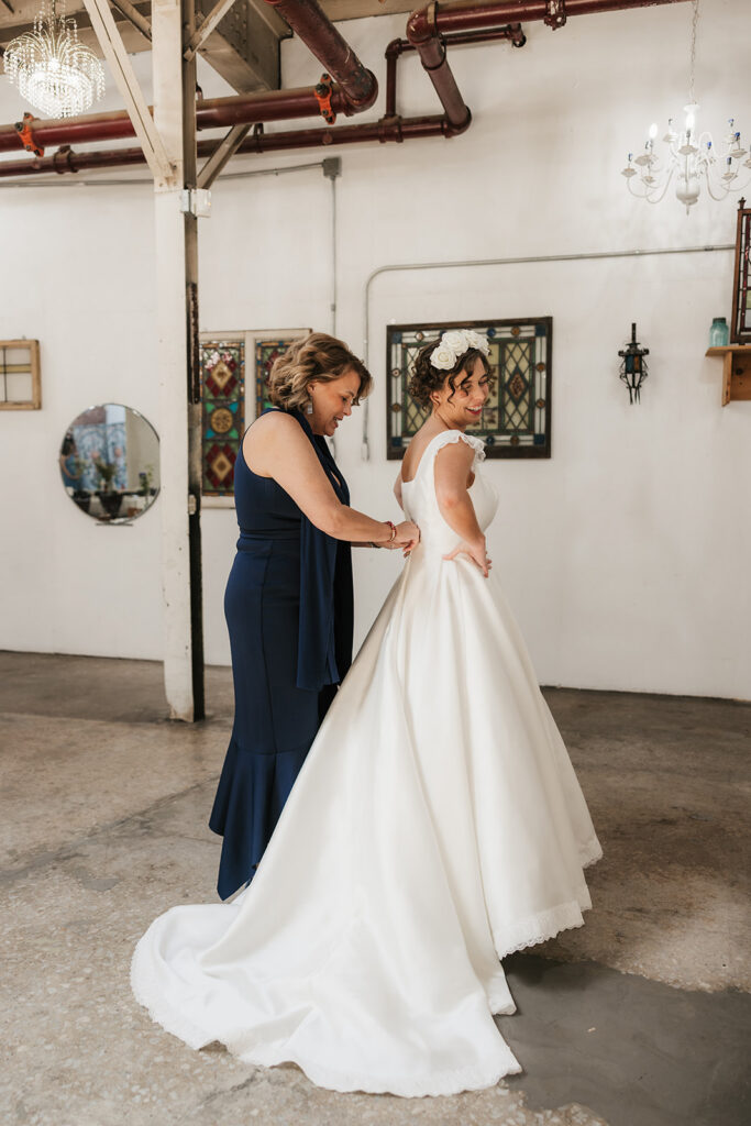 Mother of the bride helping her with the wedding dress