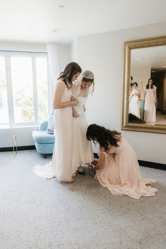 bridesmaids helping the bride with her shoes